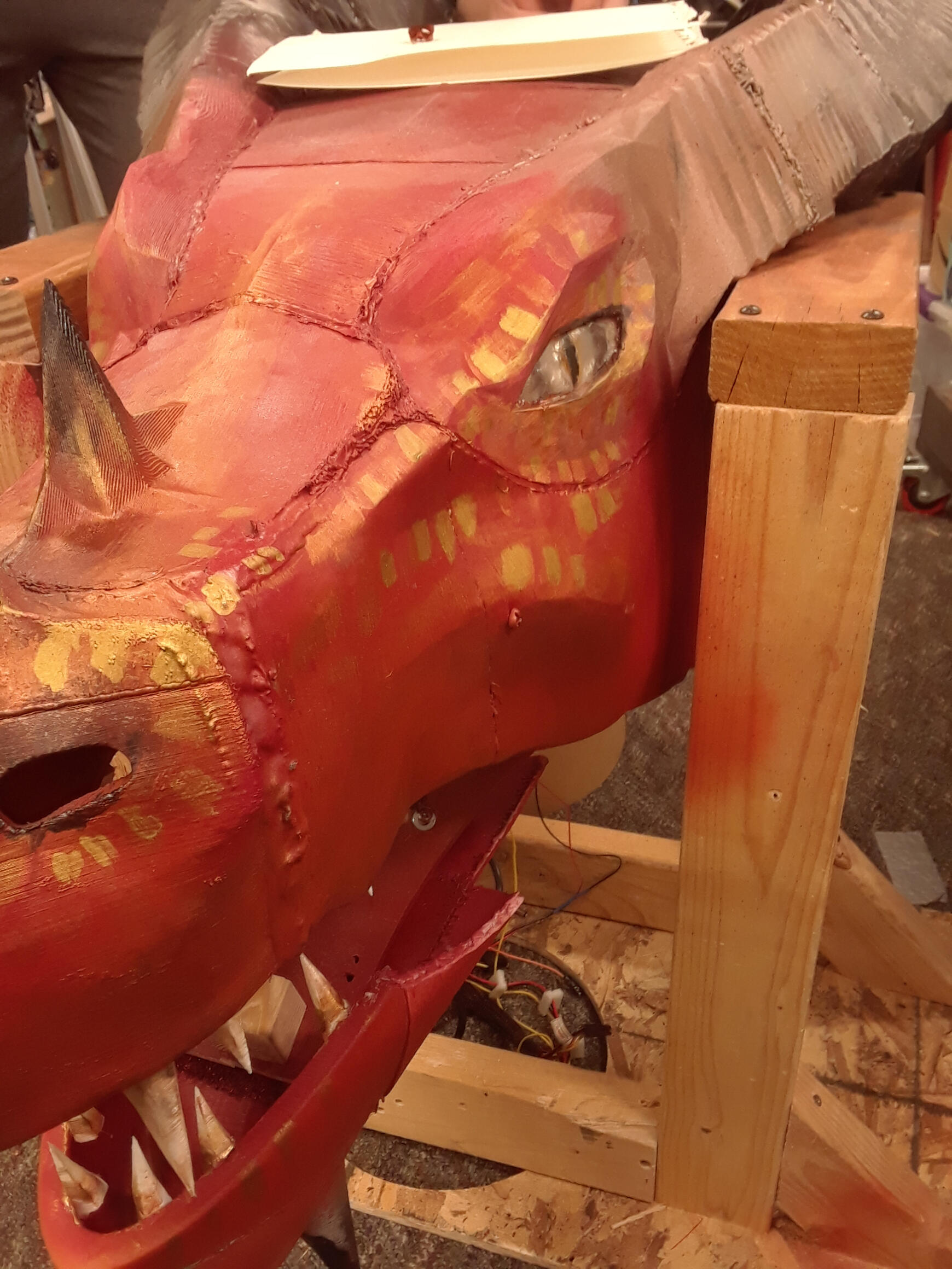 red 3d printed dragon head propped up by wood supports