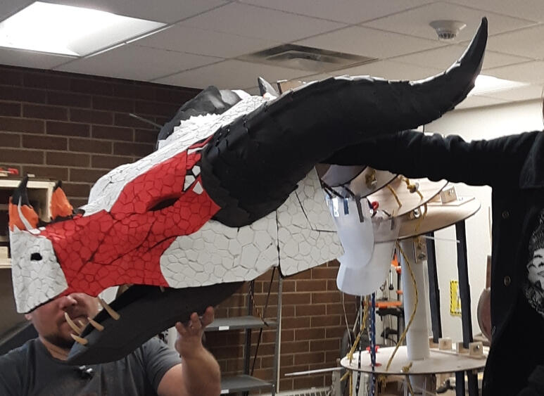 the foam dragon head mounted on an early neck armature, unpainted with the separated parts clearly distinguishable. A co worker suports the jaw, while an off camera Natasha supports the top of the skull.