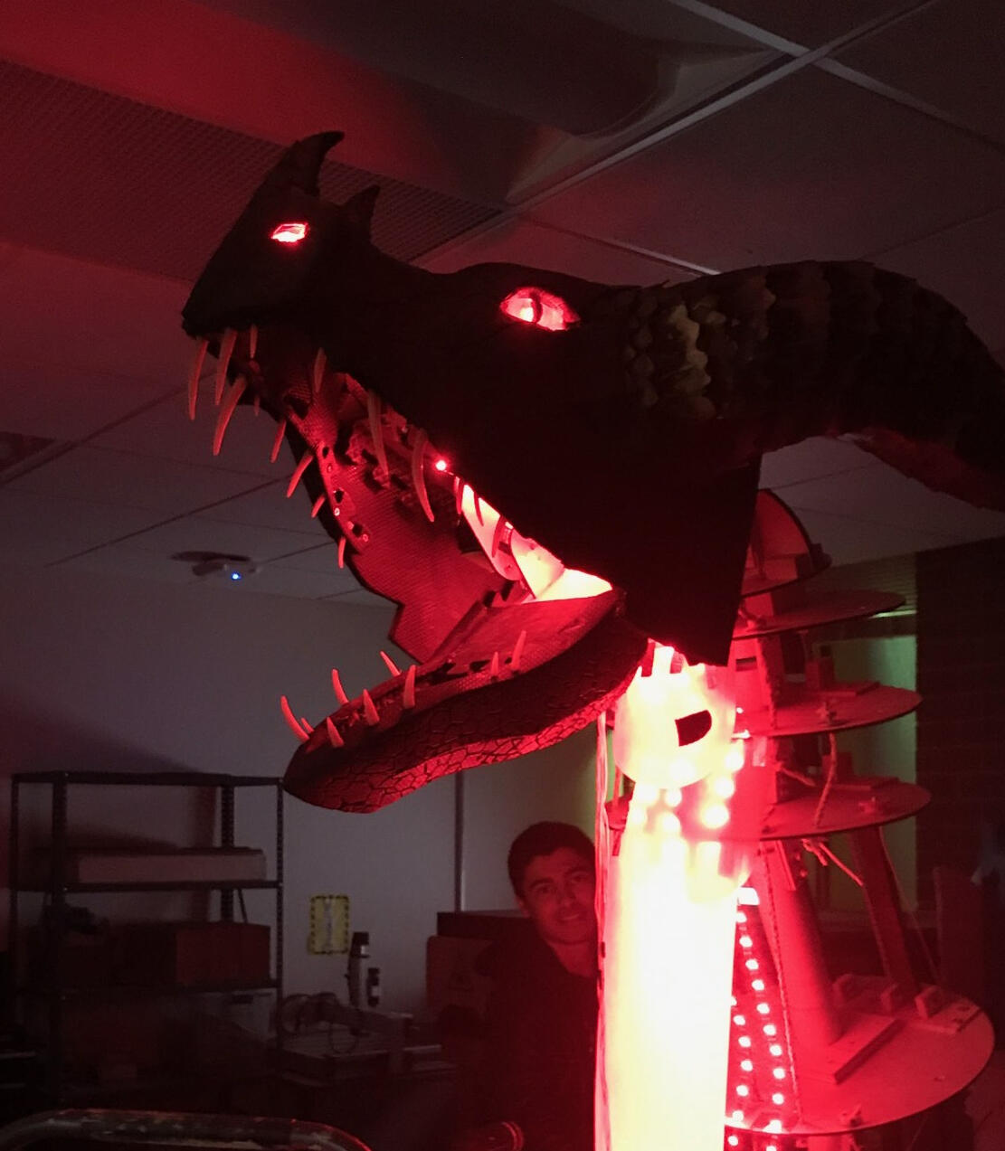 Picture of the red dragon head in the dark with it's eyes, mouth, and neck underside lit up. It is attached to an early armature that has yet to be skinned.